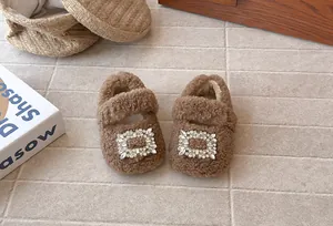 Nahaufnahme von braunen flauschigen Mädchenschuhen mit großer Strass-Schnalle Detail