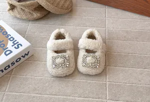 Detail von weißen Fleece-Babyschuhen mit funkelnder Strassschnalle für Mädchen.