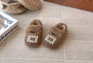 Nahaufnahme von braunen flauschigen Mädchenschuhen mit glitzernden Strass-Schnallen