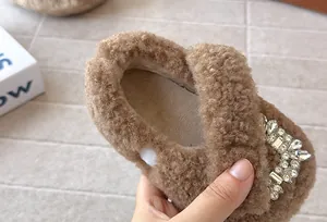 Nahaufnahme von braunen Plüschschuhen für Mädchen mit glitzernder Strassschnalle.