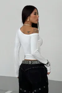 Vista posteriore donna in crop top bianco maniche lunghe spalle scoperte e jeans