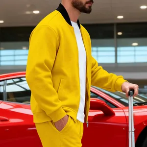 Hombre elegante en conjunto de chaqueta de chándal amarilla junto a un coche rojo en aeropuerto