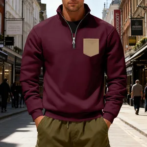 Close-up of a burgundy heavyweight fleece quarter-zip sweatshirt with a tan chest pocket