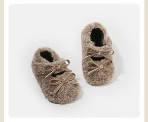 Primer plano de zapatos de peluche para bebé con lazo doble y forro polar en marrón.