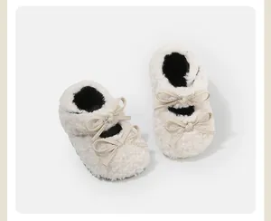 Primer plano de merceditas blancas de felpa para bebé con lazos dobles beige