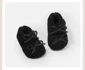 Primer plano de zapatos de bebé negros de peluche con lazos dobles y forro suave