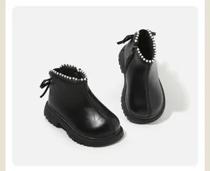 Dettaglio di stivaletti neri da bambina con bordo di perle e fiocco sul retro della scarpa