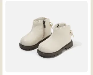 Vista dettagliata degli stivaletti crema da bambina con bordo in perle e fiocco decorativo