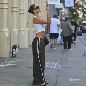 Street style view of high-waisted leopard print wide-leg pants with side stripes