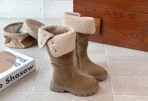 Macro view of warm children's brown suede boots with beige sherpa fleece fold-over trim