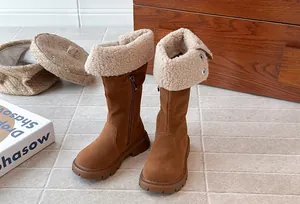 Detail view of girls' brown suede tall boots featuring warm cream shearling-lined fold-over cuffs.