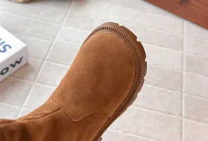 Close-up detail of warm brown suede girls' tall boots with Maillard style aesthetic