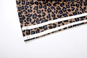 Close-up detail showing leopard print pattern and white athletic stripes on trouser hem