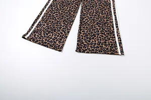 Detail of leopard print wide leg pants with white side stripe on plain background.