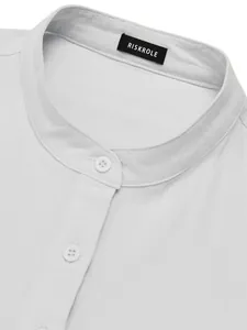 Detail shot of a white linen shirt featuring a mandarin collar and woven neck label