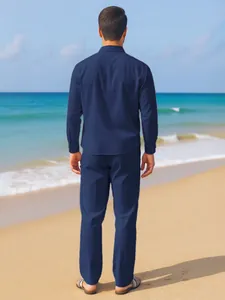 Back view of men's navy blue linen shirt and trousers set on a summer beach background