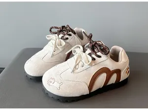 Close-up of girl's cream German army trainer shoes with cute cat embroidery detail