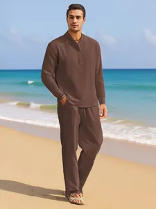 Man wearing a stylish brown linen shirt and pants set on a tropical sunny beach.