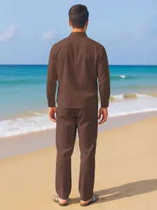Back view of men's brown linen shirt and trousers set on a sunny summer beach background