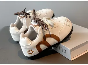 Close-up detail of girls' white retro sneakers featuring cute cat and paw embroidery.
