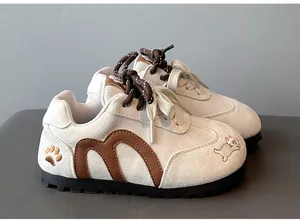 Close-up of girls' cream sneakers with brown cat embroidery and M logo details