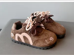 Close-up of brown suede girls' sneakers with pink M-logo and cat embroidery