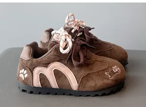 Detailed side view of brown girls' sneakers with cute cat embroidery and pink accents