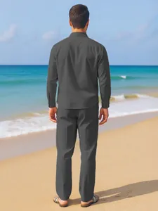 Back view of men's dark grey linen shirt and matching trousers set on a beach