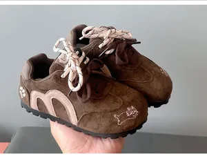 Detailed view of girls' brown suede German training shoes with cute cat embroidery.