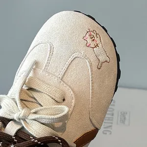 Detailed close-up of girls' beige German trainer sneakers with cute cat embroidery detail