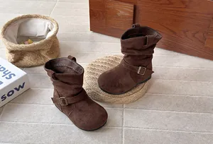Détail de bottes souples en daim marron pour filles avec boucle de style vintage.