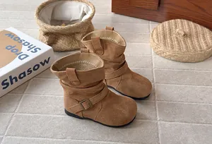 Détail en gros plan des bottes plissées en daim marron pour filles avec boucle