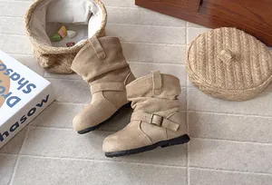 Gros plan sur les bottes plissées en daim beige avec boucle pour filles