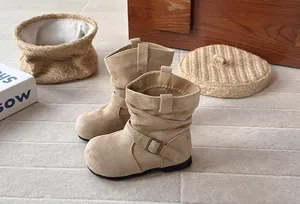 Gros plan de bottes plissées en daim beige pour filles avec boucle de style rétro.
