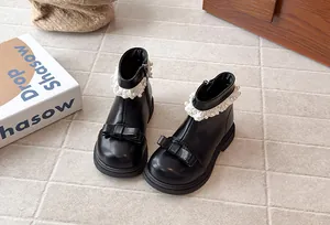 Détail de bottines noires pour filles avec nœud décoratif et bordure en dentelle perlée
