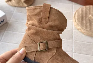 Détail en gros plan d'une botte froncée en daim marron pour fille avec boucle métal rétro.