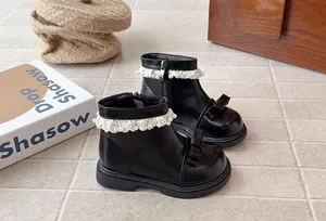 Gros plan bottines noires filles avec dentelle de perles et nœud dans un décor chaleureux