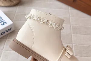 Gros plan sur la dentelle perlée et le nœud des bottines d'hiver crème pour filles