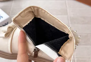 Détail de bottine pour fille avec doublure en velours noir, perles et nœud décoratif.