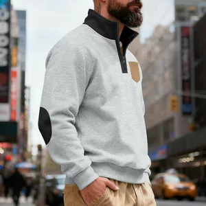 Close-up of men's grey half-zip sweatshirt with black elbow patches and tan pocket detail