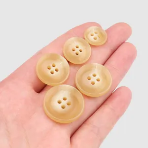 Set of premium beige urea buttons for high-end apparel held in hand for scale