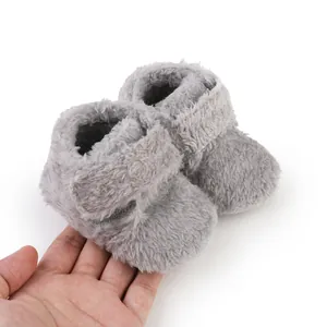 Soft gray plush baby walking shoes held in hand to show texture and scale detail