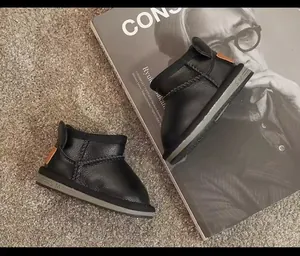 Close-up detail of black children's winter snow boots featuring a textured leather finish.