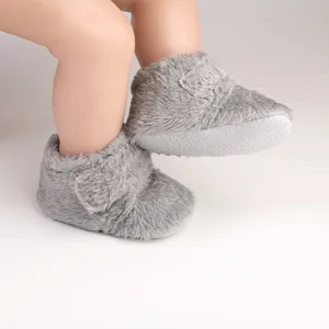 Detailed view of grey fuzzy baby booties with non-slip soles and hook-and-loop closure.