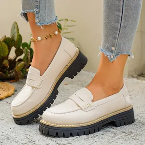 Gedetailleerde opname van beige loafers in Britse stijl met dikke zwarte profielzolen