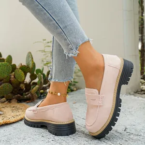 Detailopname van roze matte loafers met dikke zwarte plateauzolen en witte stiksels