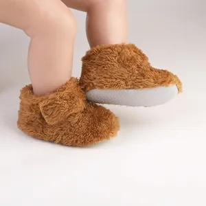Macro view of soft brown plush baby walking shoes featuring non-slip soles for infants.