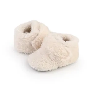 Close-up detail of soft fuzzy white baby booties with adjustable hook-and-loop strap.