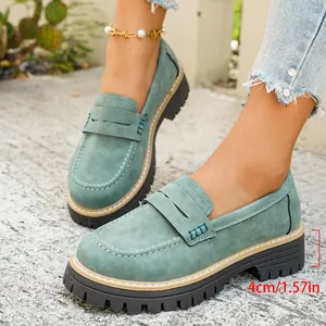 Detailopname van groene suède loafers met een stevige plateauzool van 4 cm hoog.