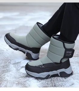 Primer plano de botas de nieve impermeables verdes y negras para niños en la nieve.